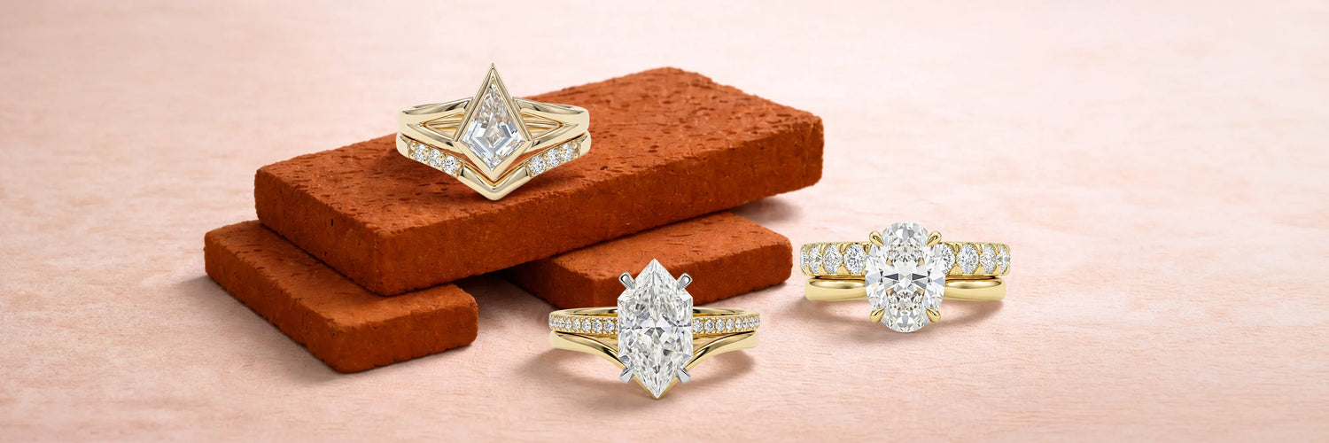 Three lab-grown diamond bridal ring sets in yellow gold — kite cut with chevron wedding band on terracotta bricks, marquise cut solitaire with pavé band, and oval cut three-stone ring with matching diamond band