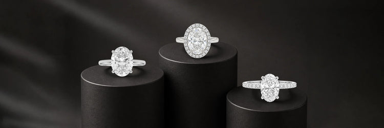 Three oval cut lab-grown diamond engagement rings in white gold — classic four-prong solitaire, oval diamond halo with pavé band, and east-west oval solitaire with full pavé band on black cylinder pedestals