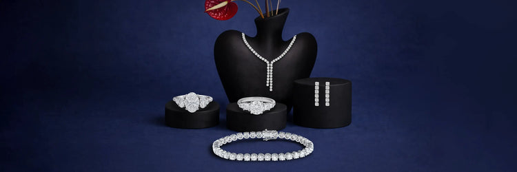 Ouros Jewels Ready To Ship Mother's Day Jewelry Collection offering lab grown diamond earrings, necklace, rings, and bracelet displayed on burgundy velvet stands with pink ribbon
