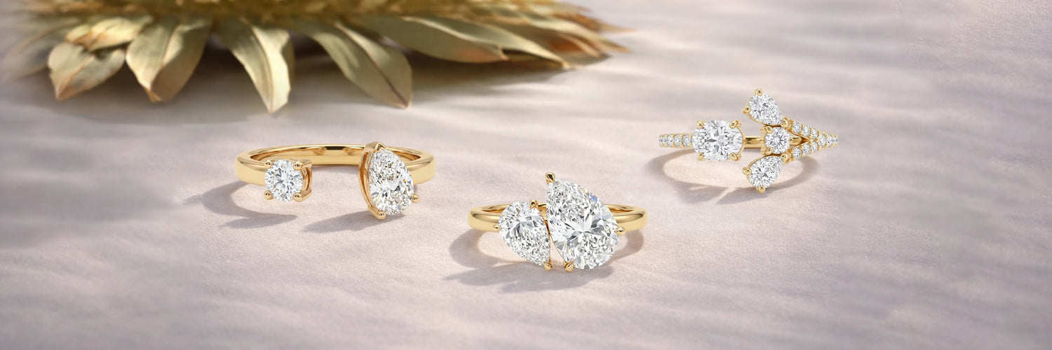 Three lab-grown diamond Toi et Moi engagement rings in yellow gold — open split shank with pear and round cut, double oval cluster solitaire, and asymmetric three-stone with round diamonds and pavé band